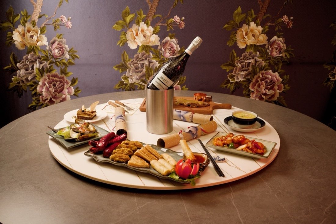 A banquet laid out on a lazy susan with a bottle in an ice bucket